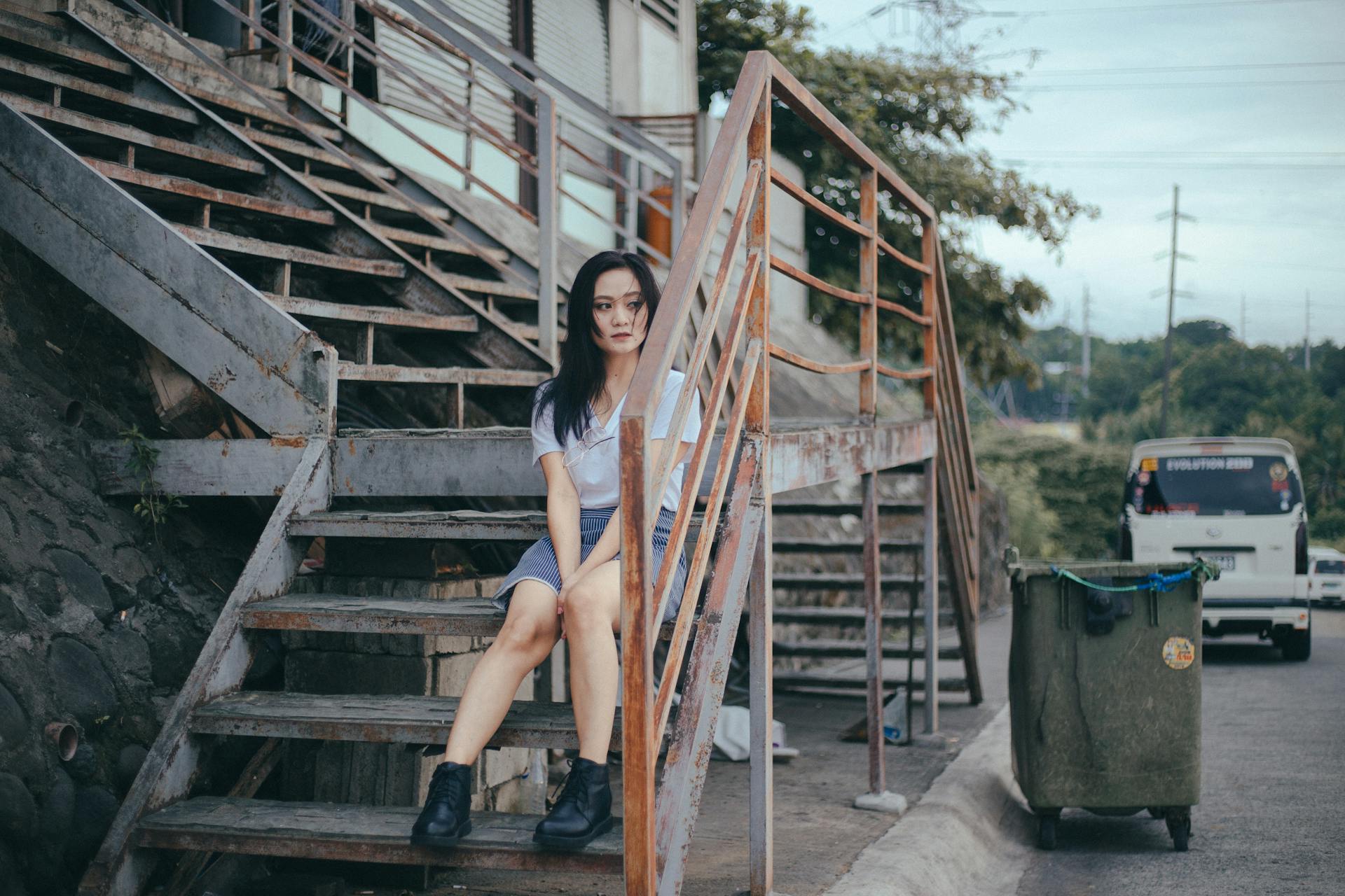 Woman sitting casually on outdoor metal stairs in an urban setting, Cavite City.