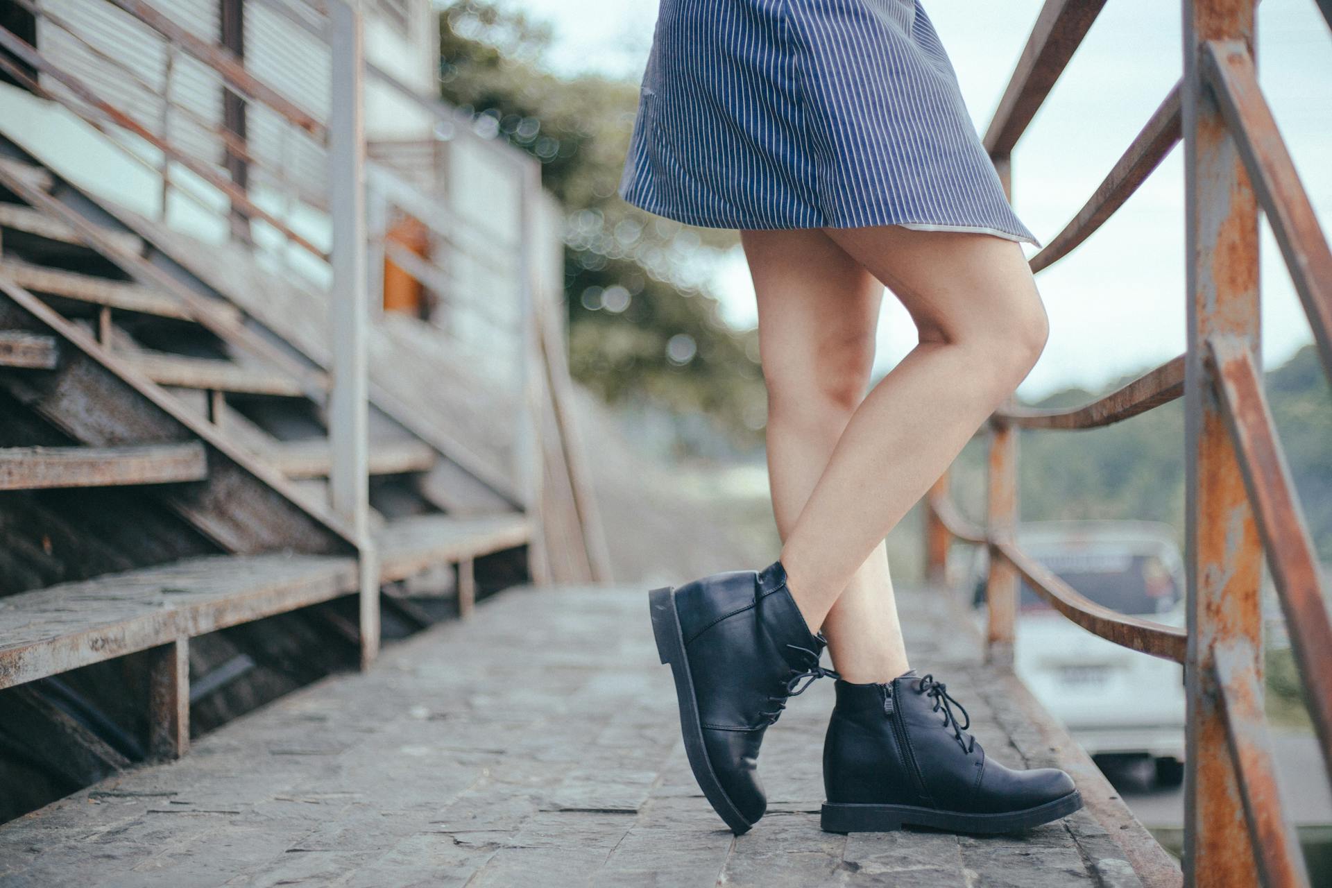 A stylish woman in boots and dress standing on rustic steps in Cavite City, Philippines.