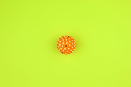 Orange and White Polka Dot Ball on Yellow Background 