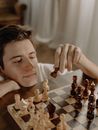 一位年轻人在家专注地进行国际象棋比赛，展现了战略与专注力