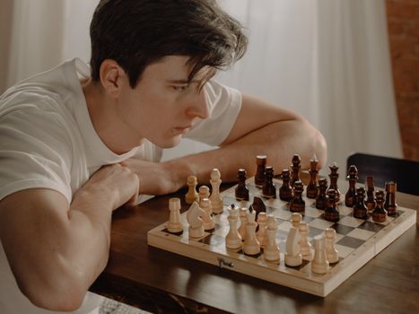 一个年轻人在家里激烈的国际象棋比赛中仔细计划着下一步行动