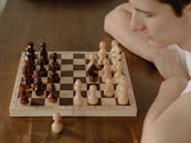 一位年轻男子在家中全神贯注地下着国际象棋，这象征着策略与专注