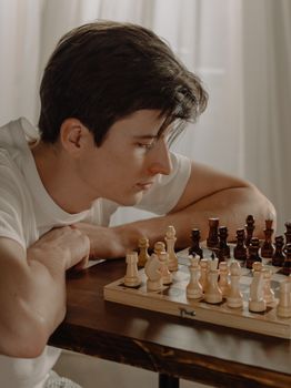 一位年轻男子在舒适的家庭环境中专注于国际象棋对弈，展现出策略与专注