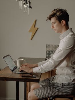 A young man working on a laptop from home, creating a cozy and professional setup.