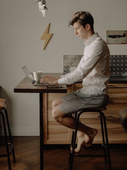 Casual work-from-home setup with a man using a laptop at a kitchen counter.