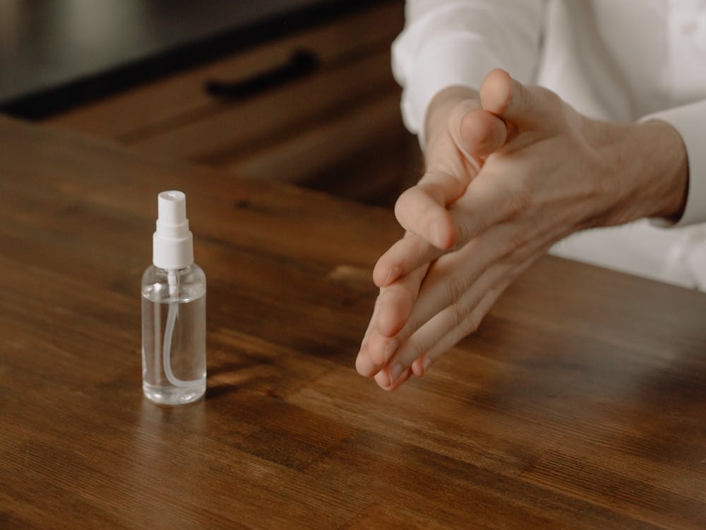 Person Holding Clear Glass Bottle