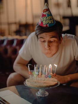 Man celebrating birthday at home blowing out candles on cake.