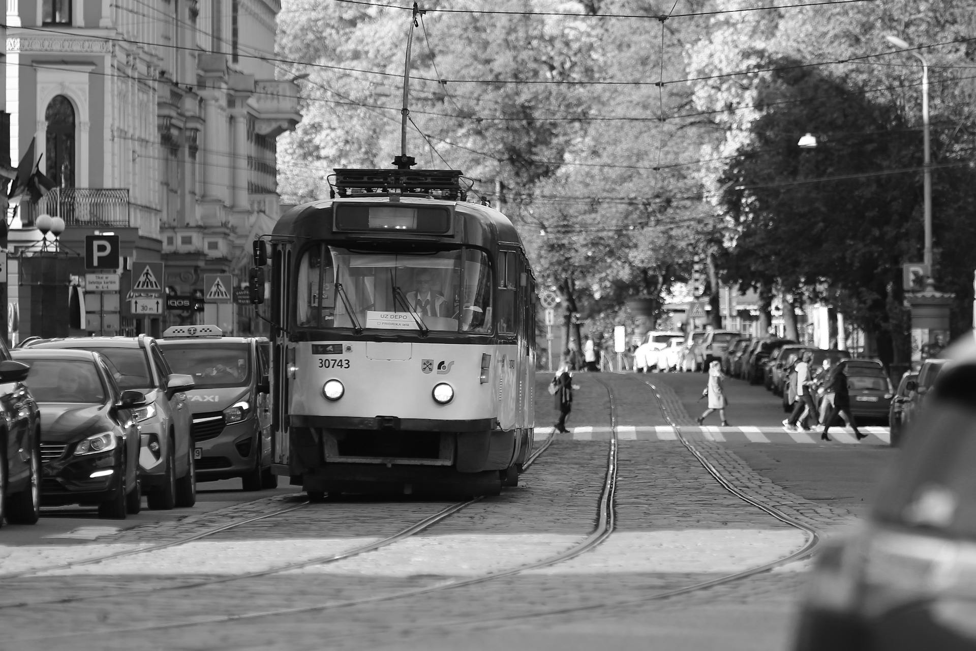 Monochrome shot of a tram amidst city traffic on a busy Riga street.