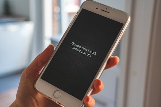 Hand holding smartphone displaying motivational quote: 'Dreams don't work unless you do.'