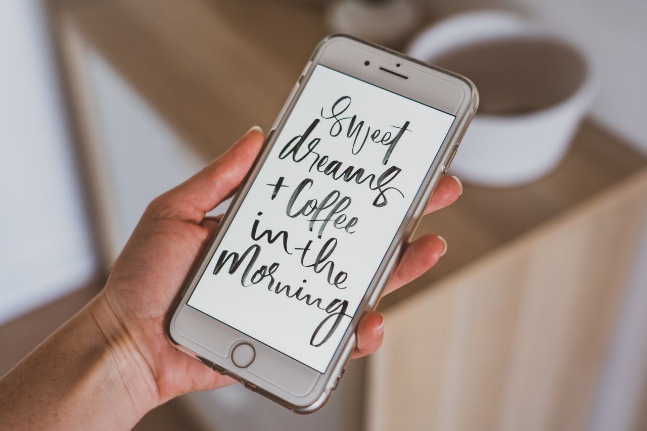 hand holding smartphone displaying motivational quote with modern call