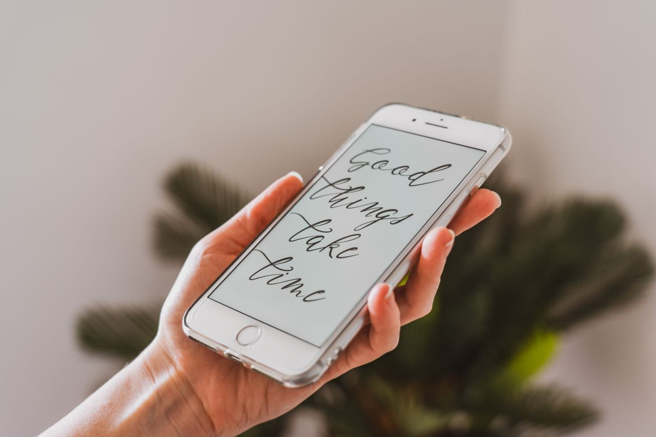 a hand holding a smartphone displaying motivational text in a bright s