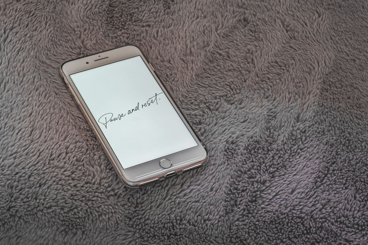 a smartphone displaying pause and reset message on a soft grey texture
