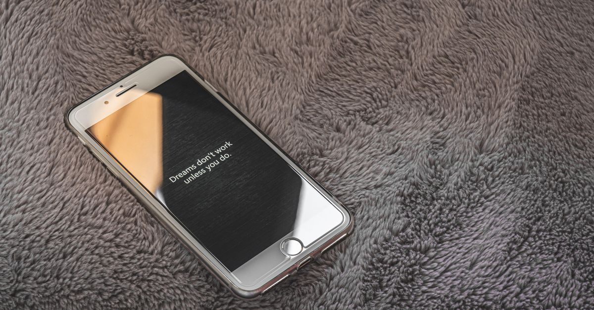 A smartphone displaying an inspirational quote on a cozy gray blanket, perfect for themes of motivation and relaxation.