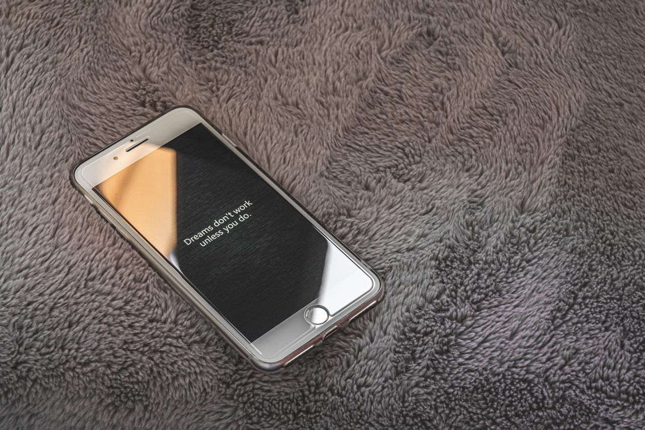 a smartphone displaying an inspirational quote on a cozy gray blanket