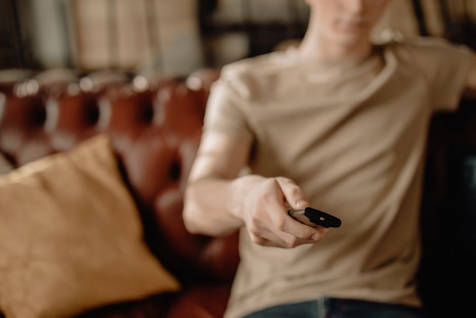 Como Lidar com o Medo de Perder o Controle na Vida Diária 2 Person relaxing on a leather sofa at home, holding a remote control. Cozy and casual atmosphere.