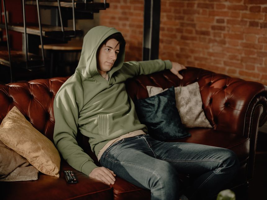 Man in a hooded sweatshirt sitting on a couch — photo by cottonbro studio on Pexels