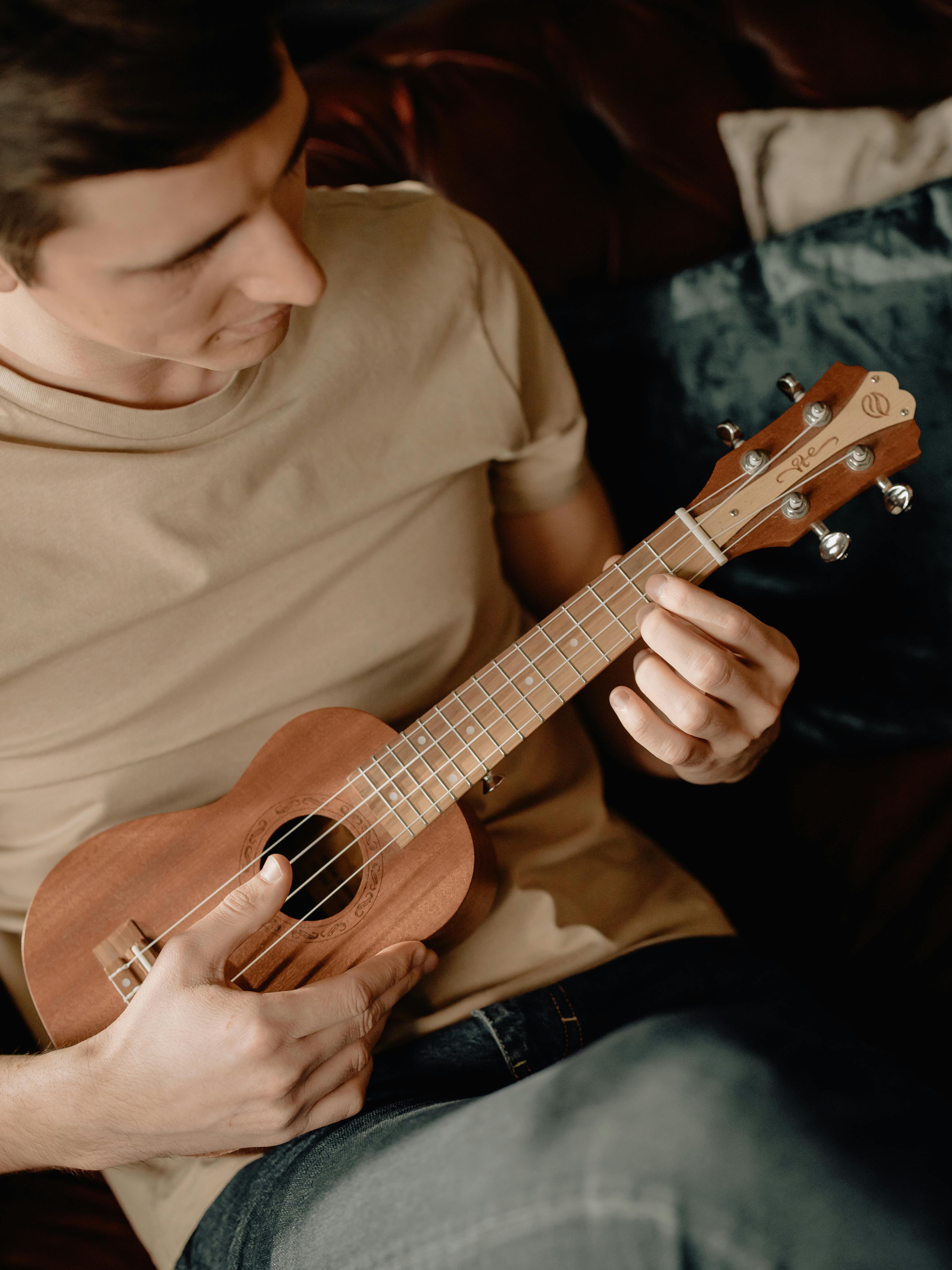 man in white crew neck t shirt playing brown acoustic guitar