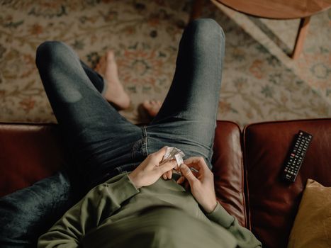 Person in Gray Jacket and Black Pants Sitting on Brown Leather Couch