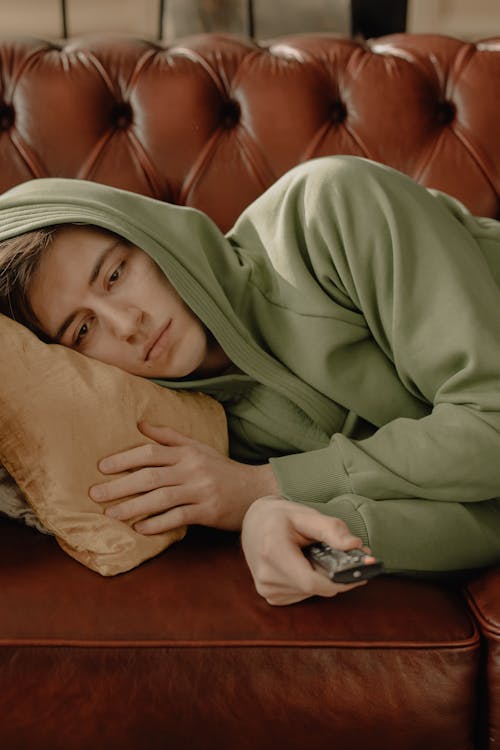 Free Woman in Brown Hoodie Lying on Bed Stock Photo