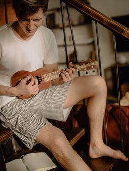 Young man enjoying a solo ukulele session at home for relaxation.
