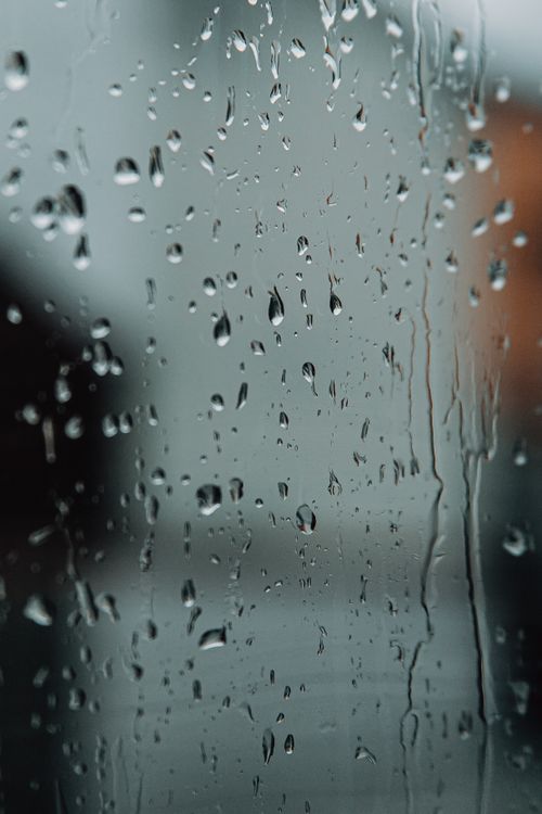 Free Transparent droplets sliding down window surface and glistening while raining outside on blurred background Stock Photo