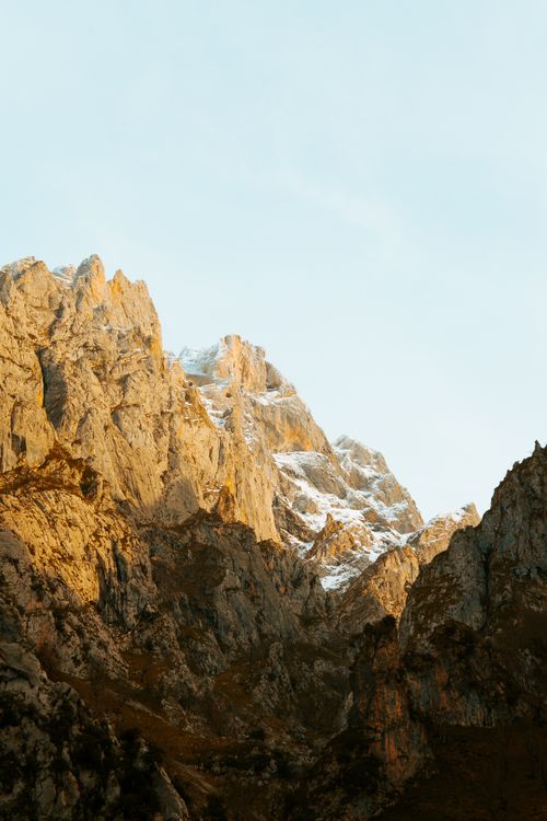 Free View of light blue cloudless sky above slopes and barren rocks covered with snow Stock Photo
