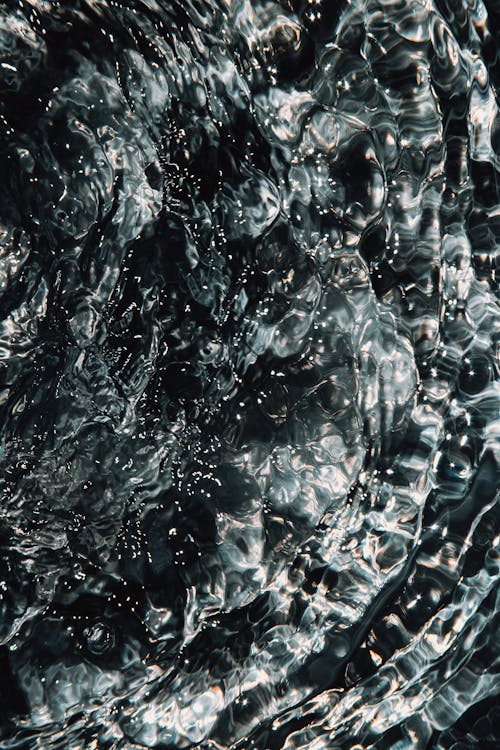 Splash of transparent liquid and rounds on water surface in reservoir in daylight