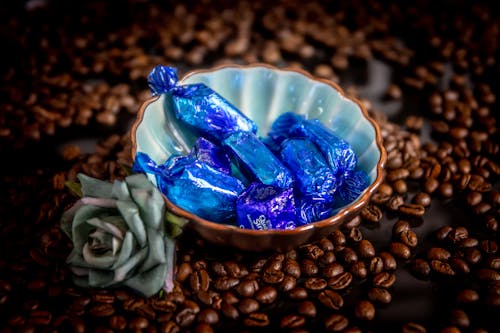 Blue Wrapped Candies Inside A Bowl Beside Flower