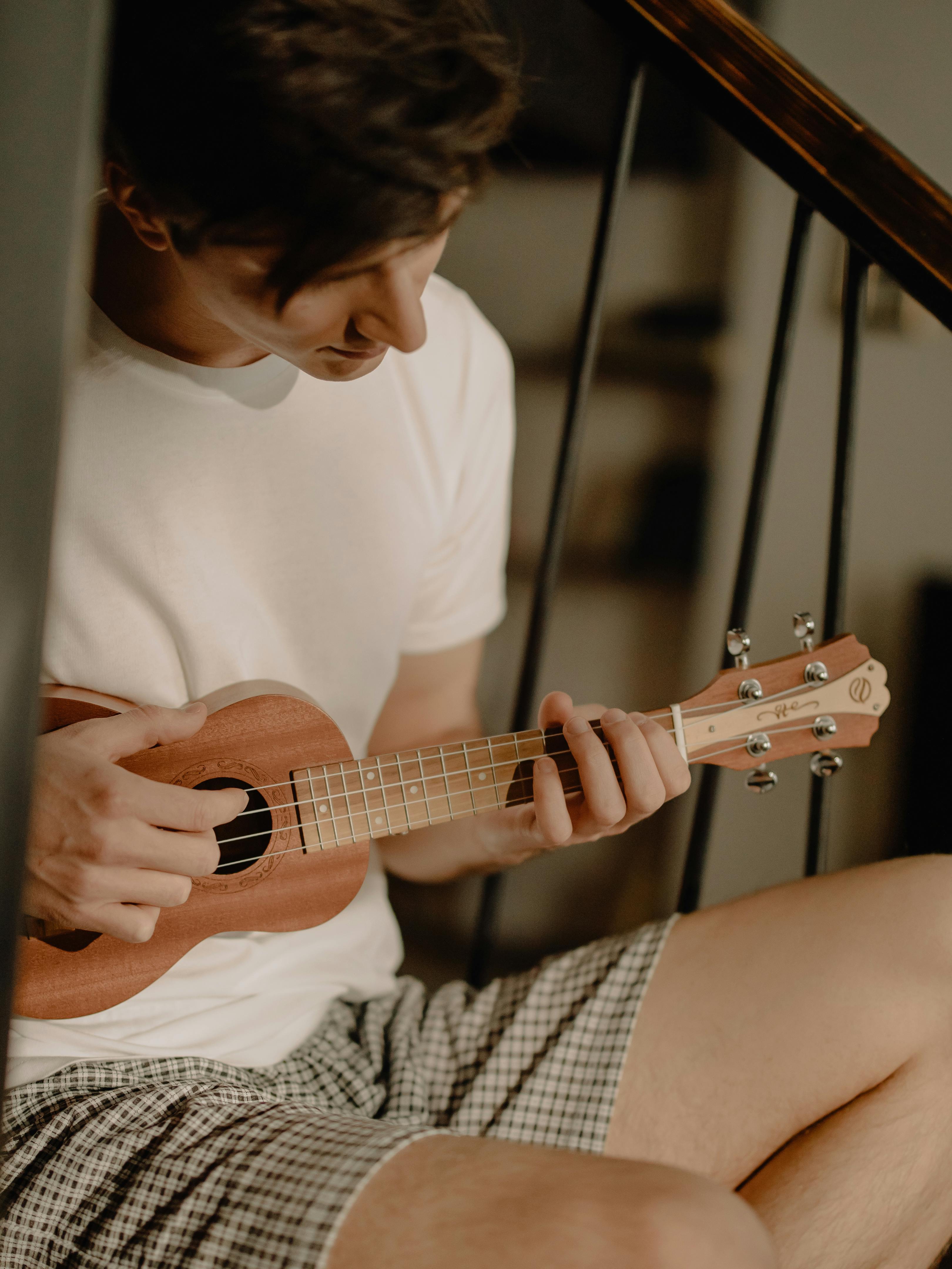 woman in white crew neck t shirt playing brown acoustic guitar