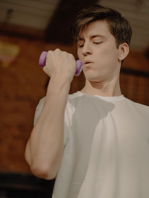 Man in white t-shirt lifting dumbbell for exercise at home. Man in white t-shirt lifting dumbbell for exercise at home.