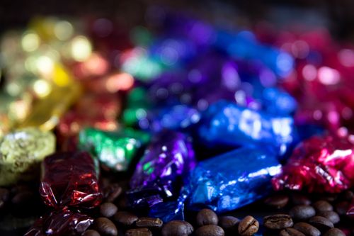 Free Close-up of colorful wrapped candies on coffee beans. Artistic bokeh background. Stock Photo