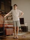 Man in White Crew Neck T-shirt and Gray Shorts Standing on Brown Wooden Staircase