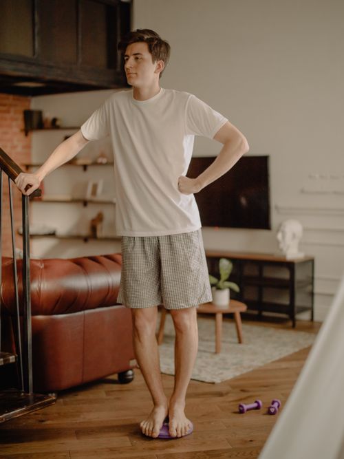 Free A young man enjoying a quiet moment at home in comfortable attire, standing in a cozy living room. Stock Photo