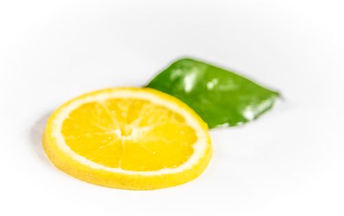 Free Close-up of a fresh orange slice and green leaf on a white background, showcasing vibrant color contrast. Stock Photo