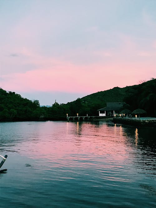 Rippling surface of peaceful lake with embankment in park under colorful sunset sky