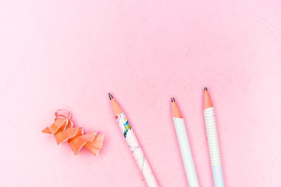 Three decorative pencils and shavings on a pink surface, offering stationery inspiration.