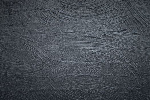Close-up of a textured dark gray concrete wall with abstract patterns.