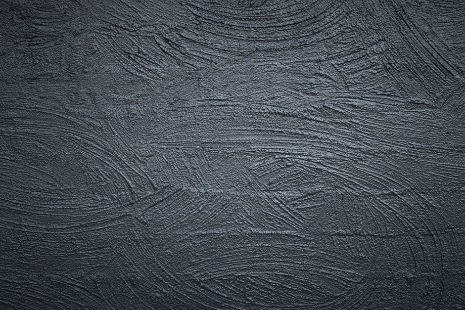 Close-up of a textured dark gray concrete wall with abstract patterns.