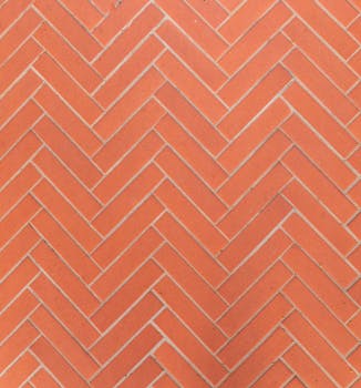 Close-up of a herringbone patterned red brick wall, perfect for backgrounds or textures.