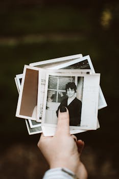 Close-up of hand holding vintage instant photos with blurred background.