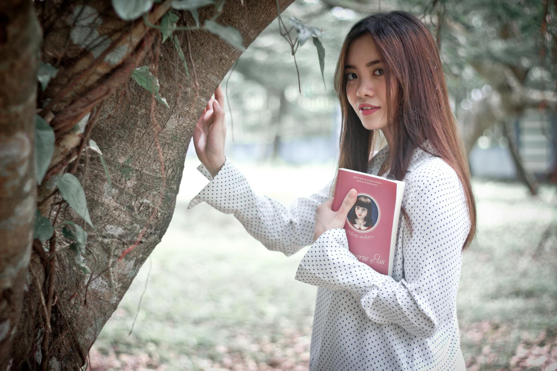 Asian woman enjoying a book and nature in Cavite City, Philippines.