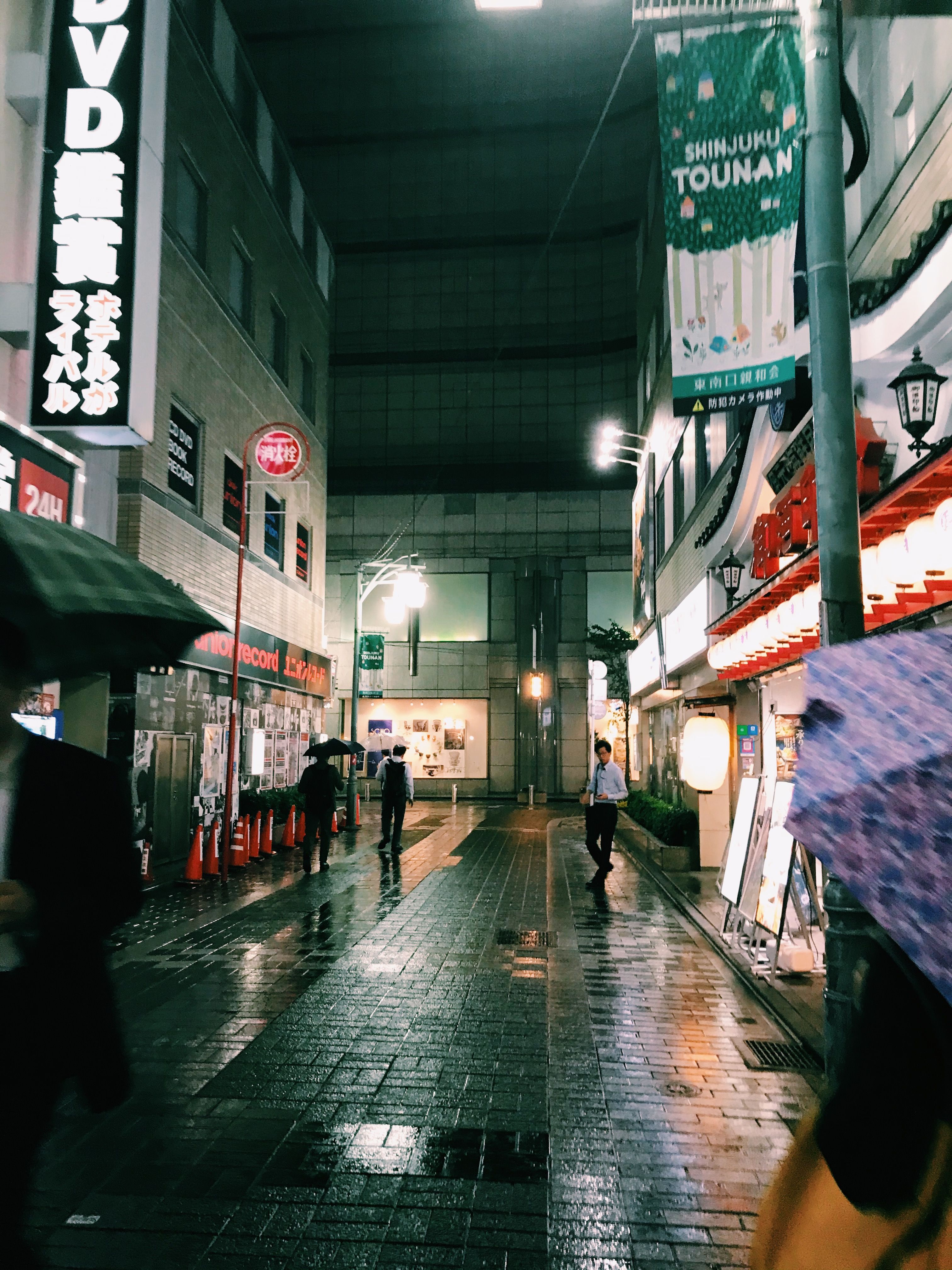 新宿潮湿的夜景中，充满活力的灯光映照在人行道上