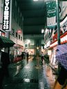 新宿潮湿的夜景中，充满活力的灯光映照在人行道上