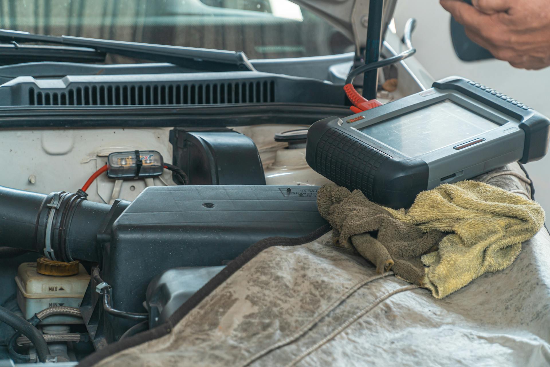 Close-up of a car engine inspection using a diagnostic tool in a garage setting, showcasing automotive maintenance and repair.