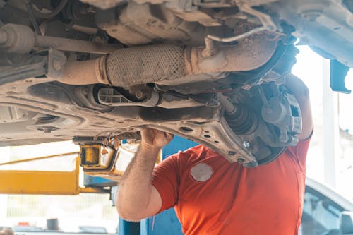 A Person in Orange Shirt Checking the Car Suspension