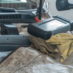A black diagnostic handset resting on a car's engine bay
