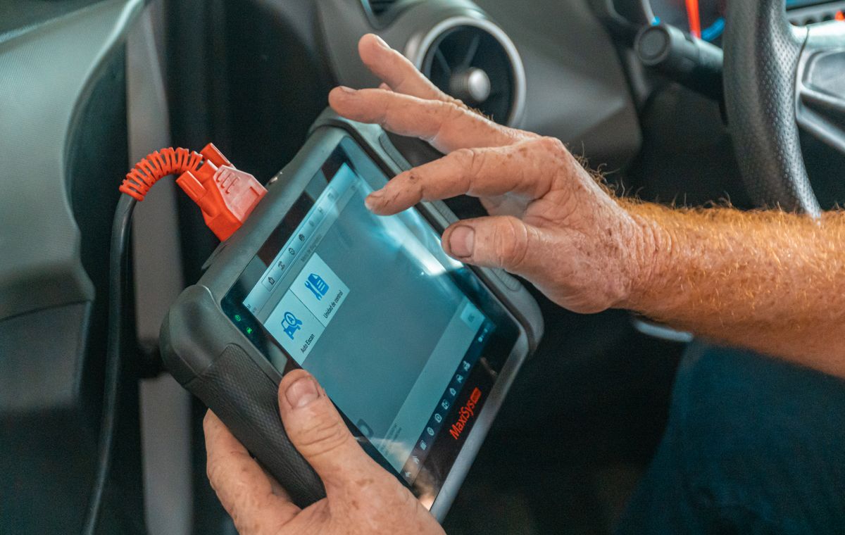 Technician using a diagnostic scanner on a vehicle