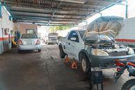 Indoor car repair garage with multiple vehicles under maintenance, showcasing a bustling automotive environment.