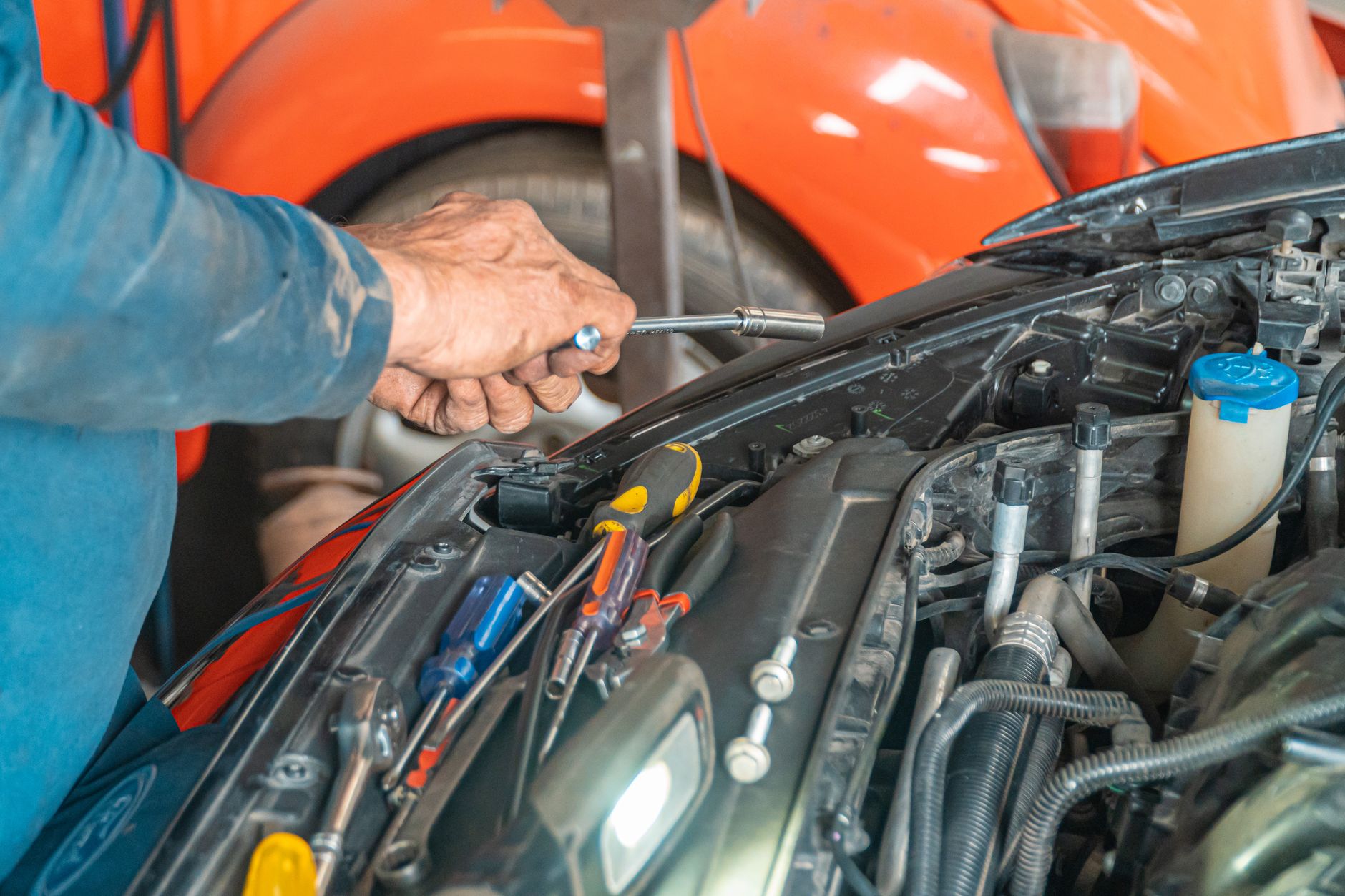 Professioneller Mechaniker führt einen Ölwechsel und Motorcheck in einer gut beleuchteten Kfz-Werkstatt durch