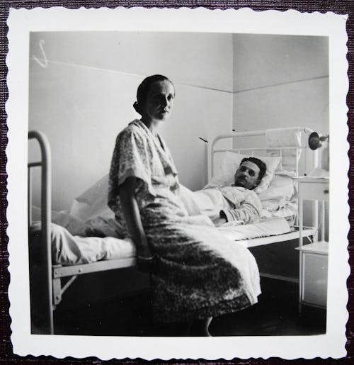 Free Aged photography of man lying on bed in hospital bed with woman sitting nearby Stock Photo